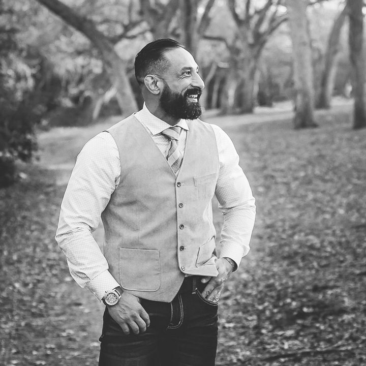 Guy Valentino outdoors in a vest, laughing, black and white.